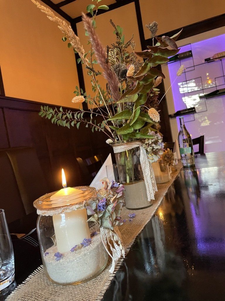 Ein Tisch mit einer Blumenvase und einer Kerze darauf.