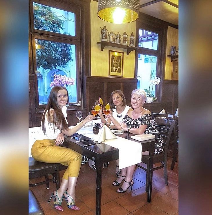 Drei Frauen sitzen an einem Tisch in einem Restaurant und stoßen mit Weingläsern an