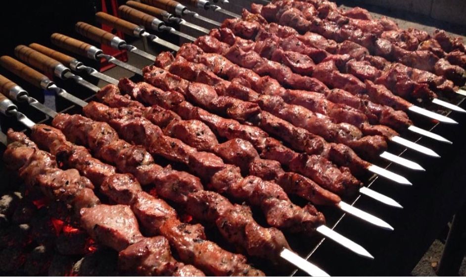 Ein Haufen Fleisch am Spieß, das auf einem Grill zubereitet wird