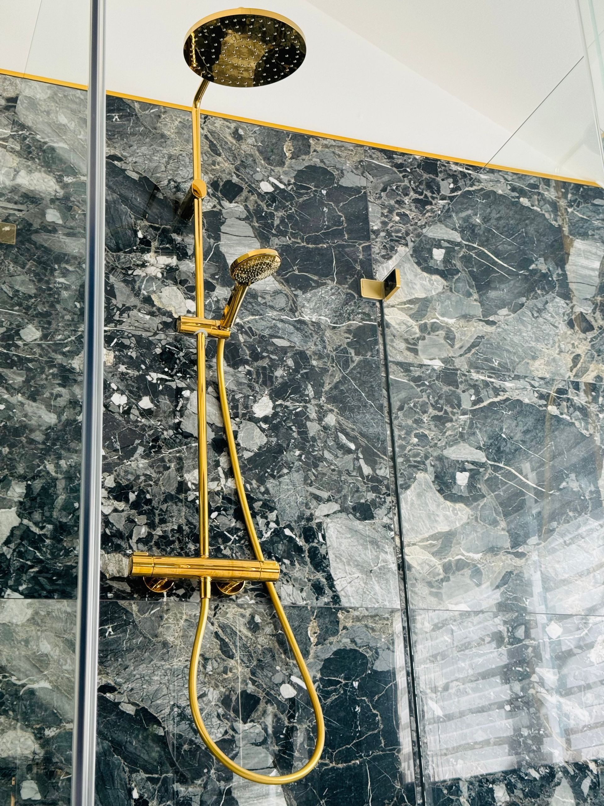 Ein goldener Duschkopf hängt von der Decke in einem Badezimmer