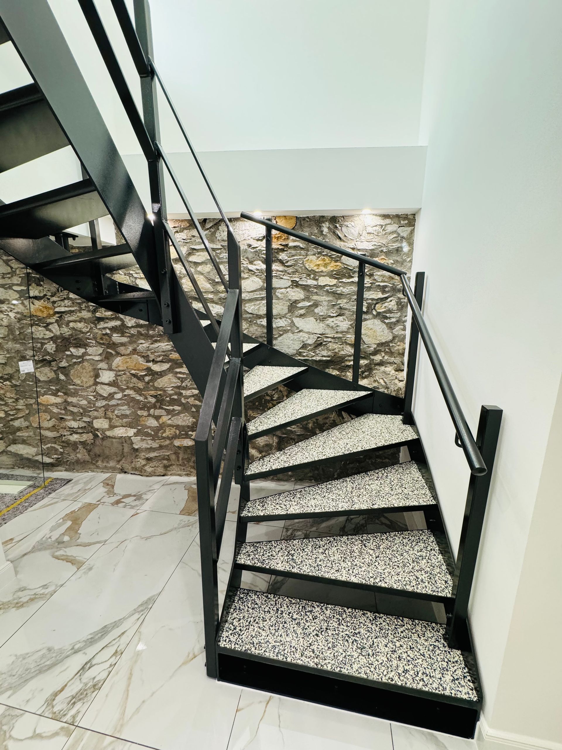 Eine Wendeltreppe mit einer Steinmauer im Hintergrund.