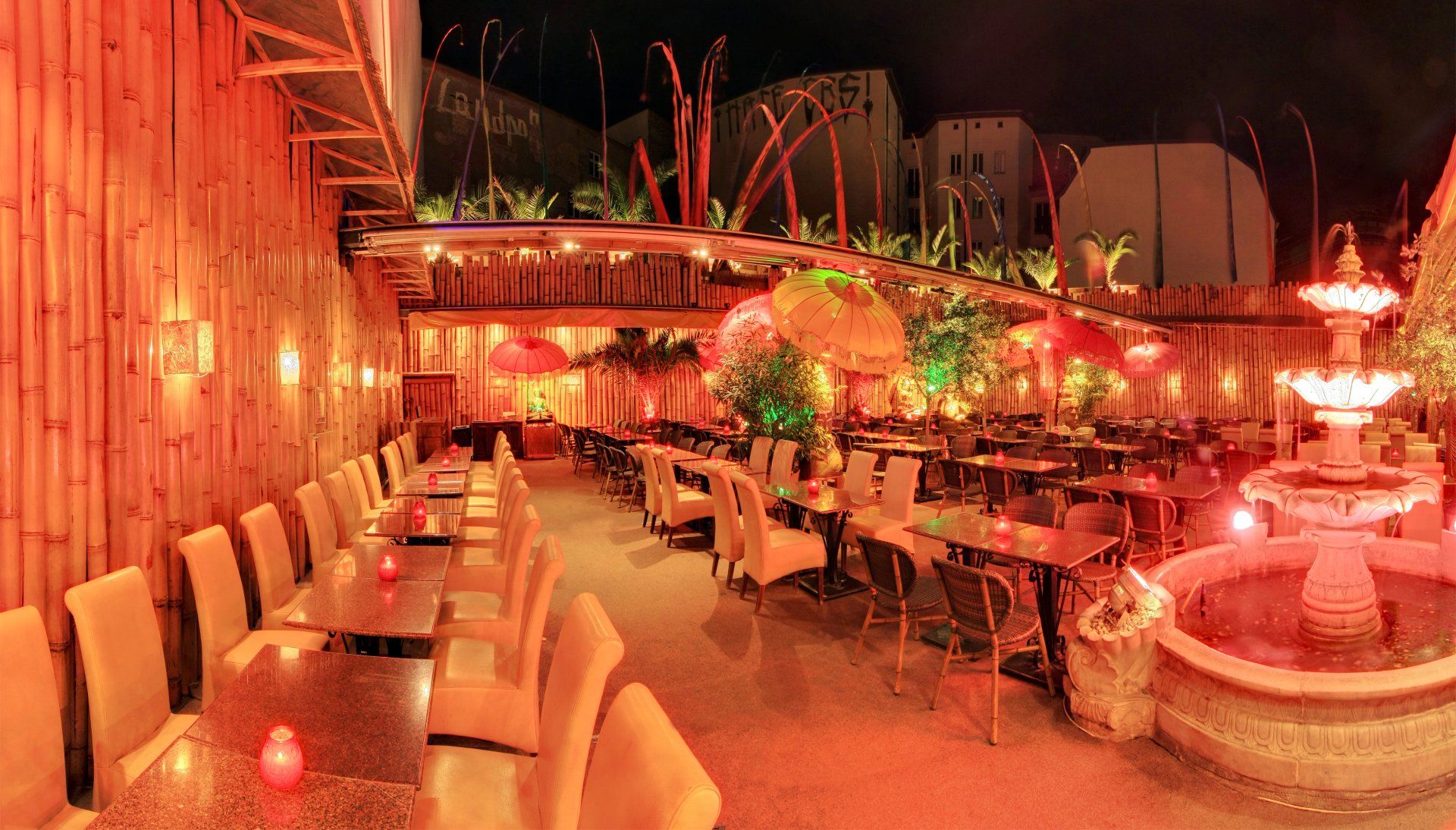 Ein Restaurant mit Tischen und Stühlen und einem Brunnen bei Nacht.