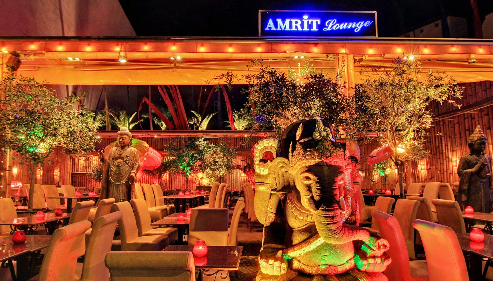 Ein Restaurant mit Tischen und Stühlen und einem Schild mit der Aufschrift „Amrit Lounge“.