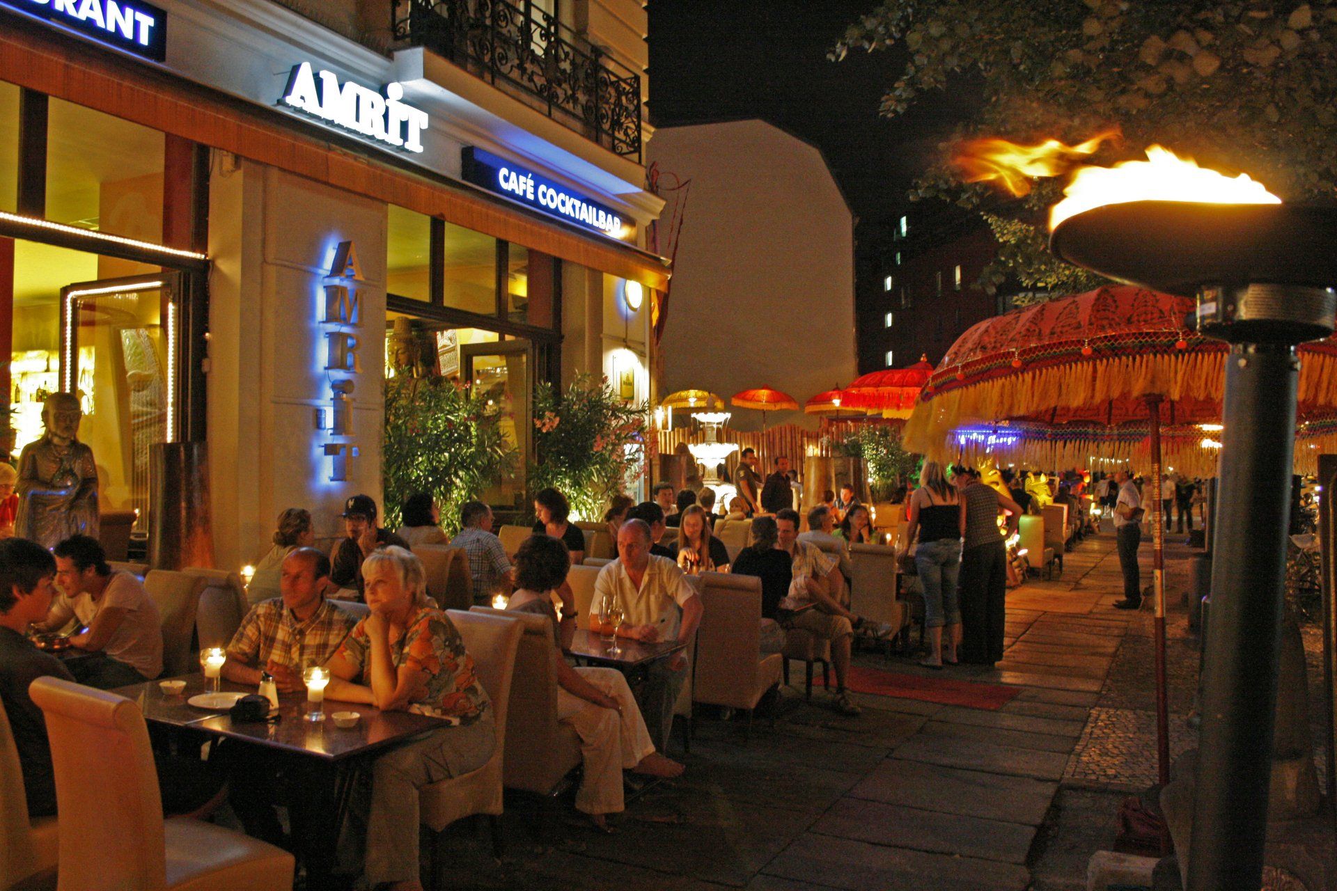 Leute sitzen an Tischen vor einem Restaurant namens Amit