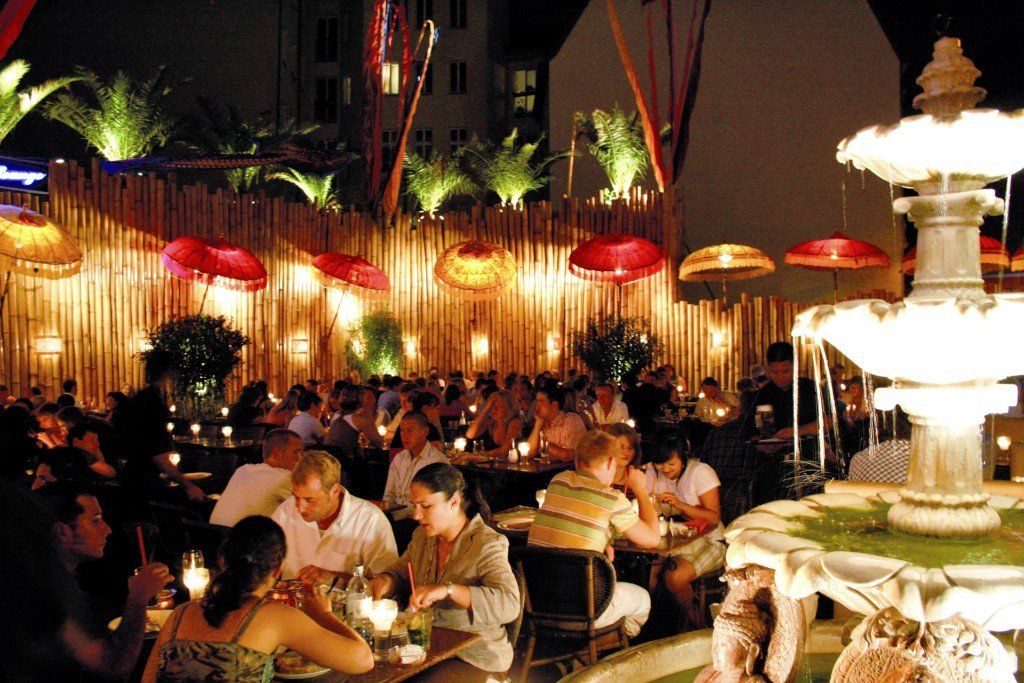 Eine Gruppe von Menschen, die an Tischen vor einem Brunnen sitzen