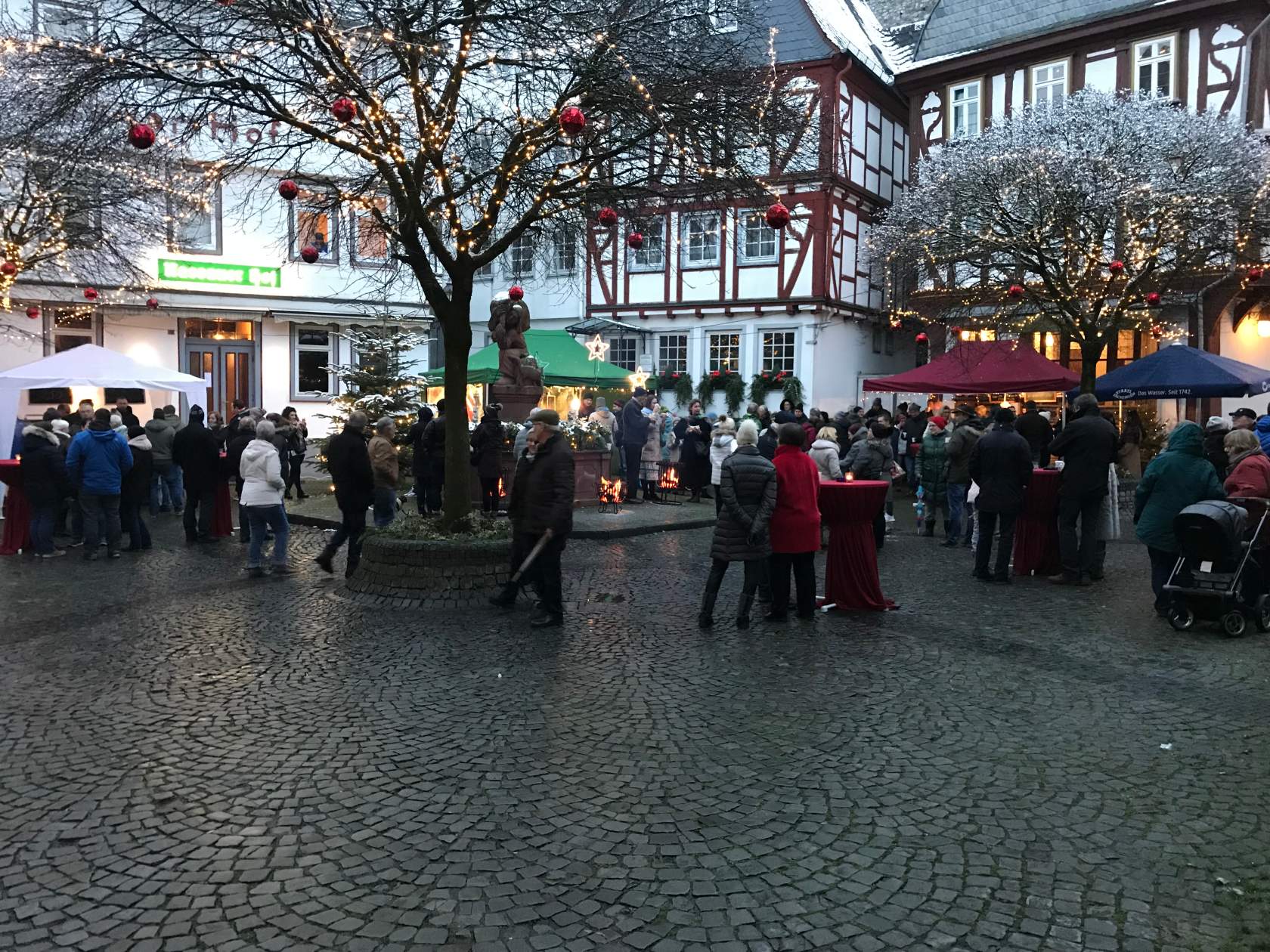 Eine Gruppe von Menschen steht auf einer Kopfsteinpflasterstraße vor einem Gebäude.