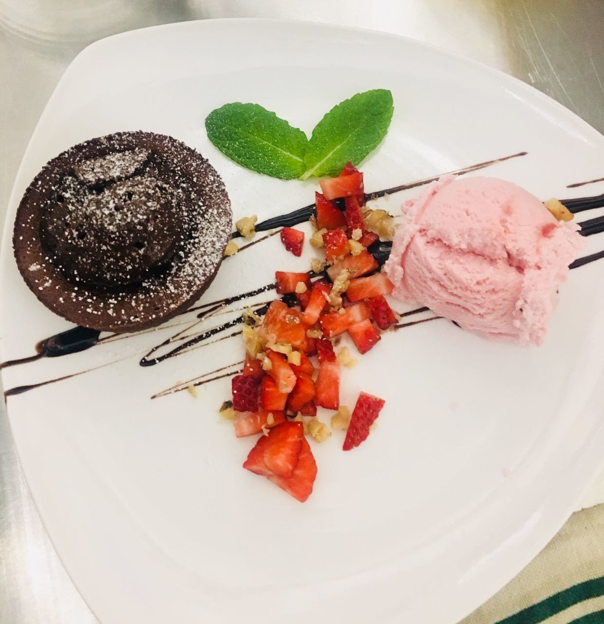 Ein weißer Teller mit einem Schokoladenkuchen und einer Kugel Erdbeereis