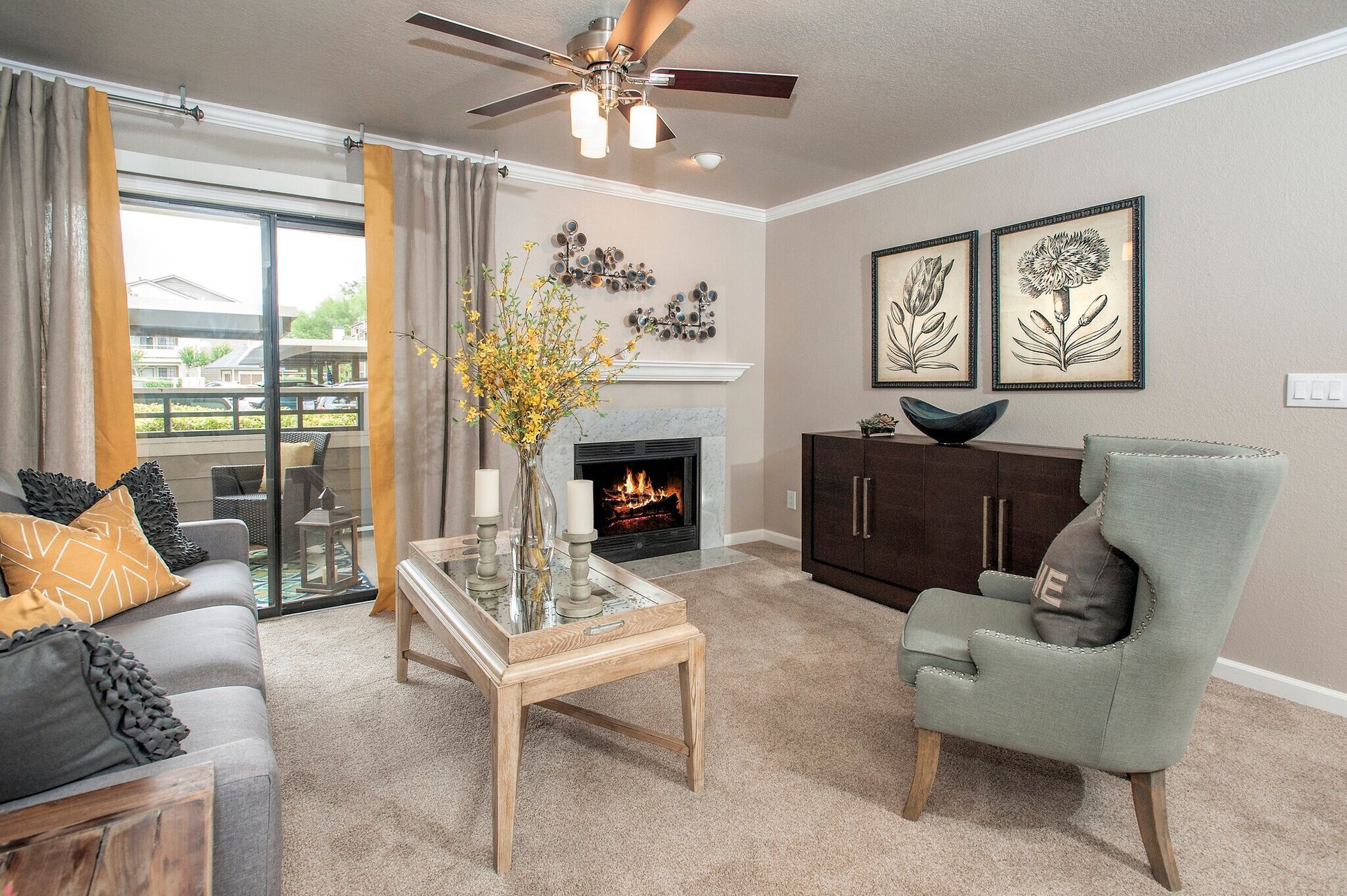Cozy living room with fireplace, gray sofa, floral decorations, and a balcony view.