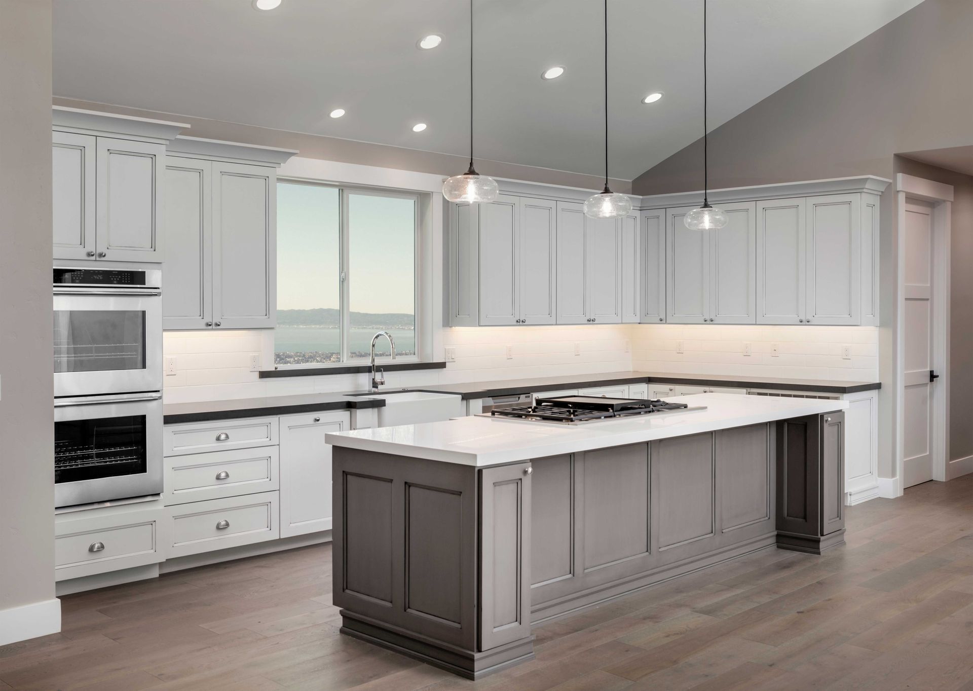 Bright modern kitchen with white cabinets, large island, and stainless steel appliances Bright modern kitchen with white cabinets, large island, and stainless steel appliances