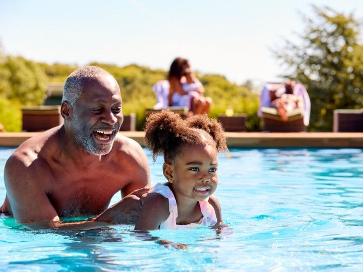 A man and a little girl are playing in a swimming pool.
