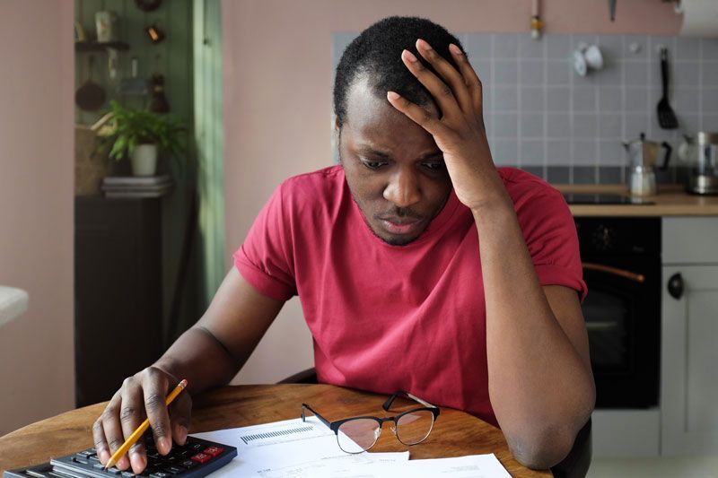 A man is sitting at a table using a calculator.