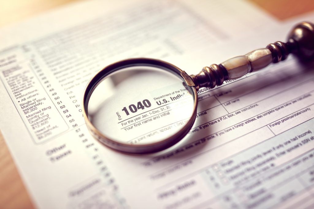 A magnifying glass is sitting on top of a tax form.