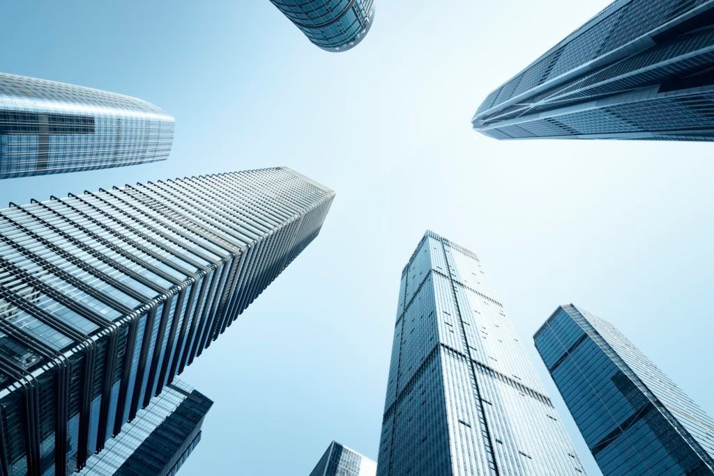 Looking up at a group of skyscrapers against a blue sky.