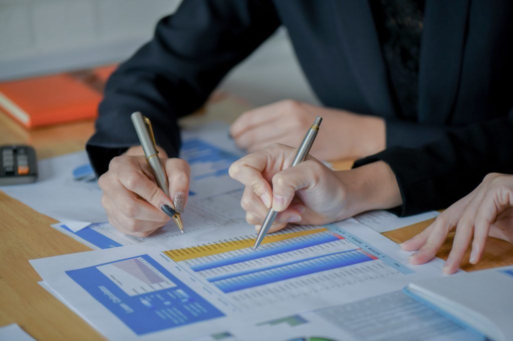 A group of people are sitting at a table writing on a piece of paper.