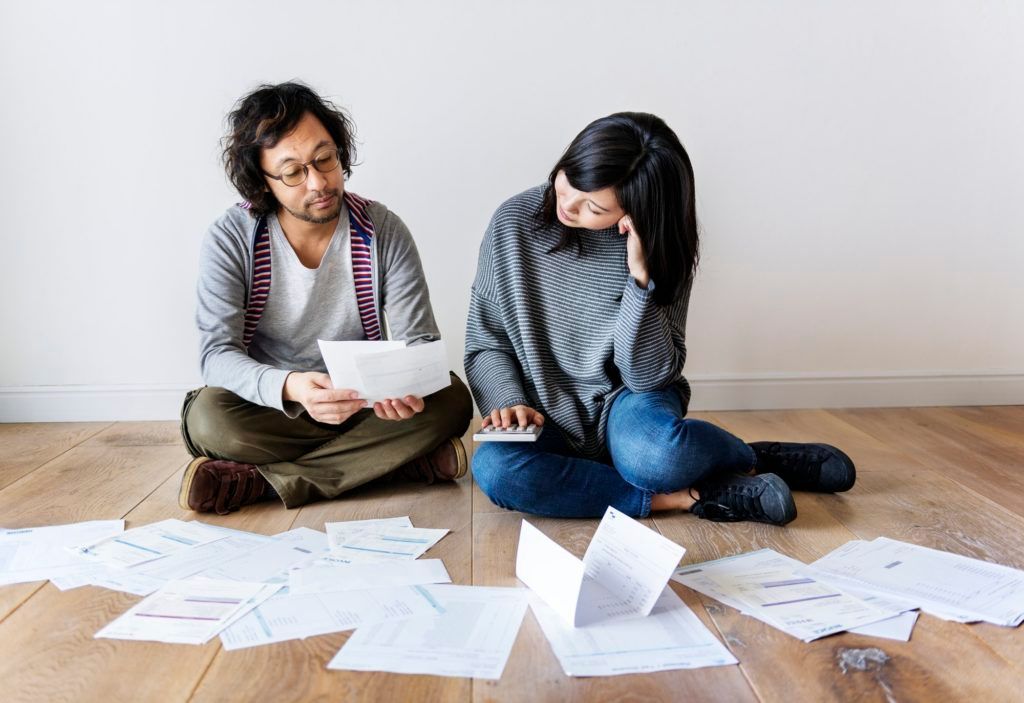 A man and a woman are sitting on the floor looking at papers.