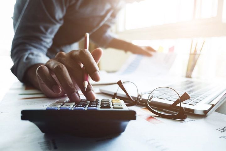 A man is using a calculator and writing on a piece of paper.