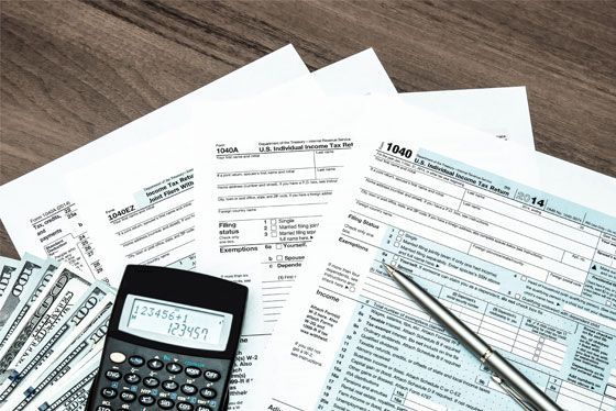 A calculator is sitting on top of a pile of tax forms.