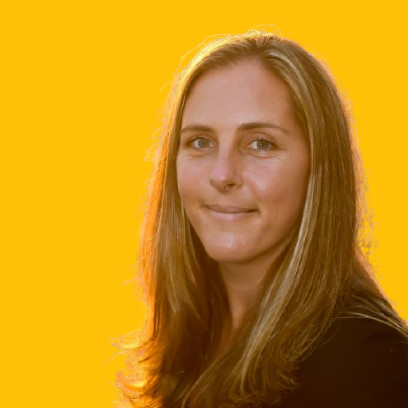 A woman with long hair is smiling in front of a yellow background.