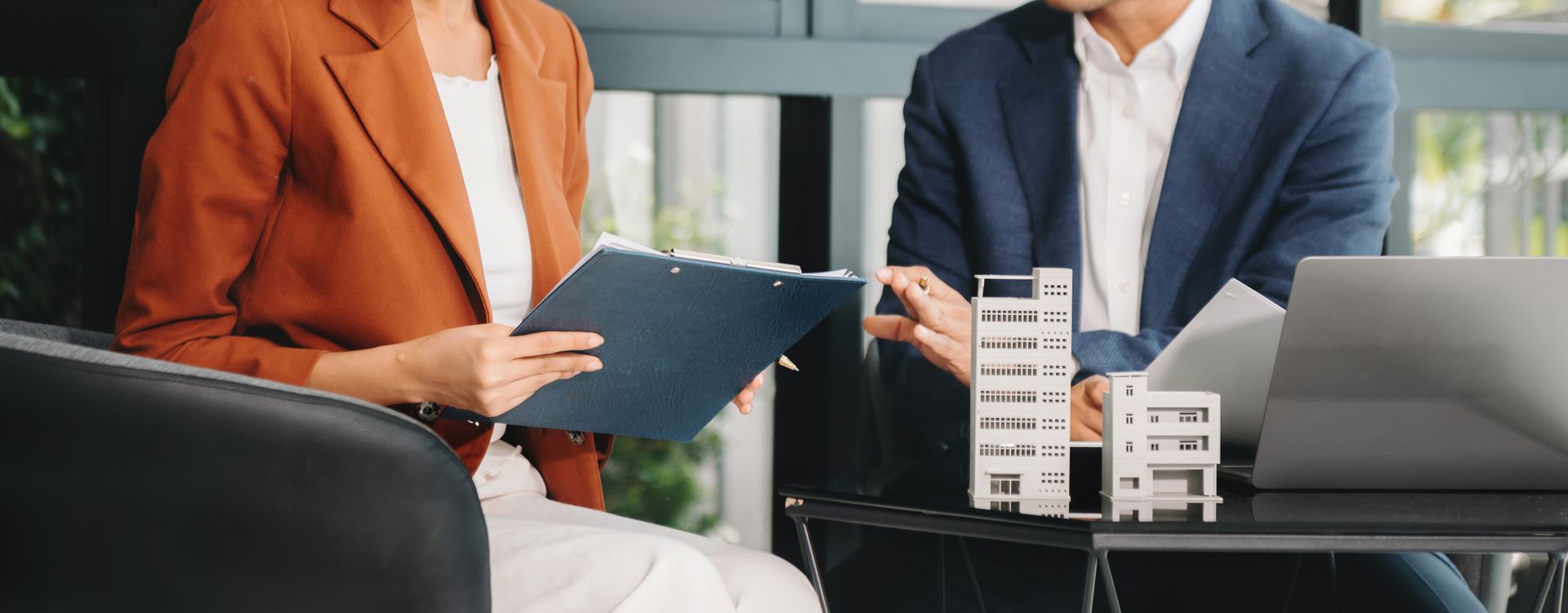 A man and a woman are sitting on a couch looking at a laptop.