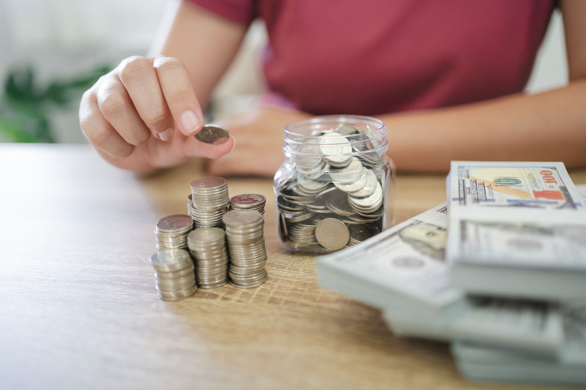A person is putting a coin into a jar of coins.