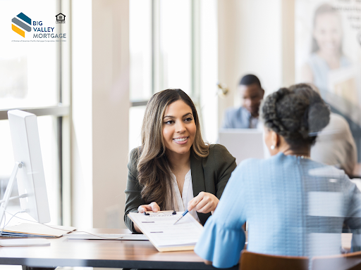 Woman in a suit reviews paperwork with another woman at a desk