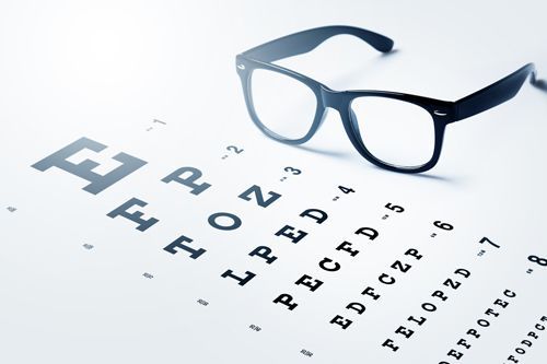 A Pair Of Glasses Is Sitting On Top Of An Eye Chart - Rochester, MN - Gibbons Optical