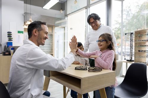 A Doctor Is Giving A High Five To A Little Girl In An Optical Shop - Rochester, MN - Gibbons Optical