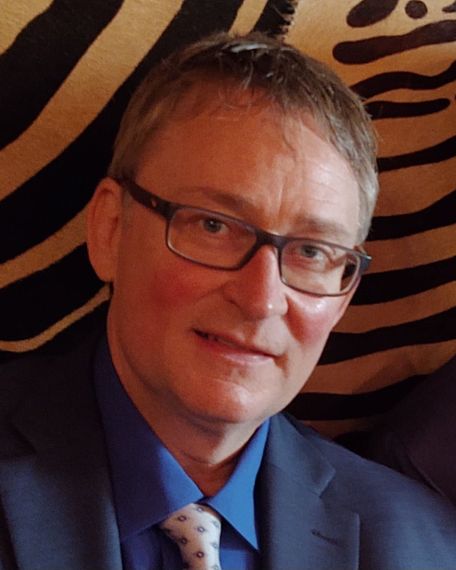 A man in a suit and tie is smiling for the camera.