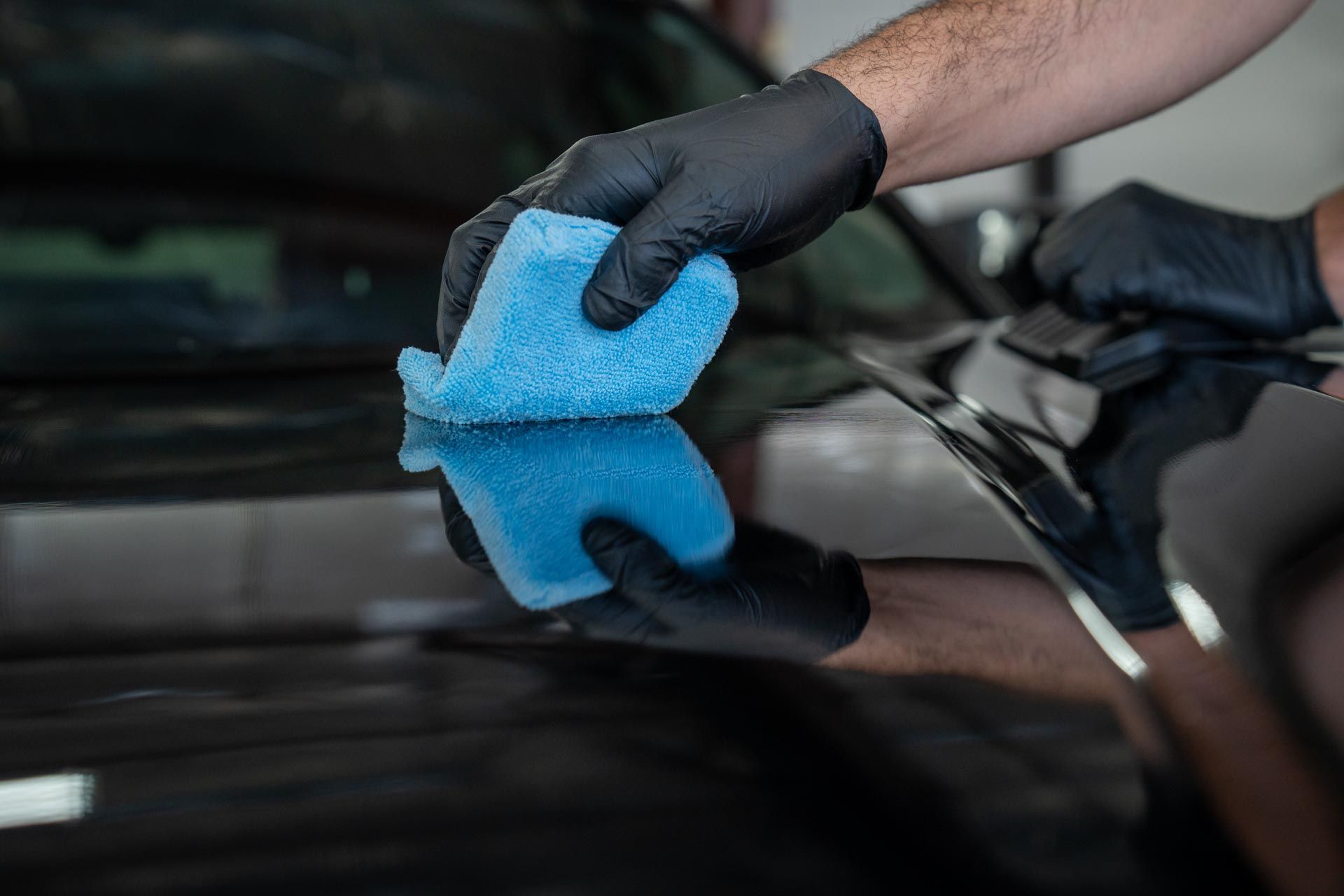 A person is cleaning a car with a blue sponge.
