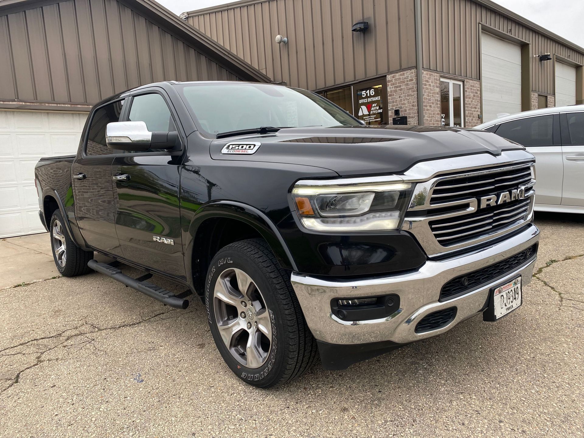 A black ram 1500 truck is parked in front of a garage.