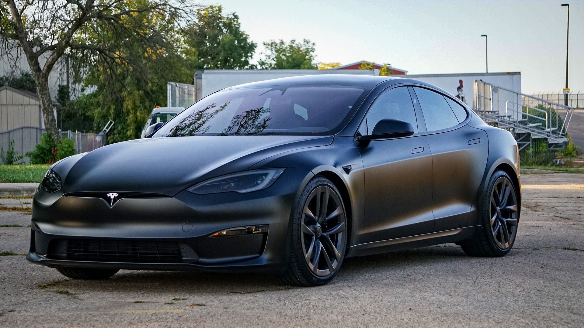 A black tesla model s is parked in a parking lot.