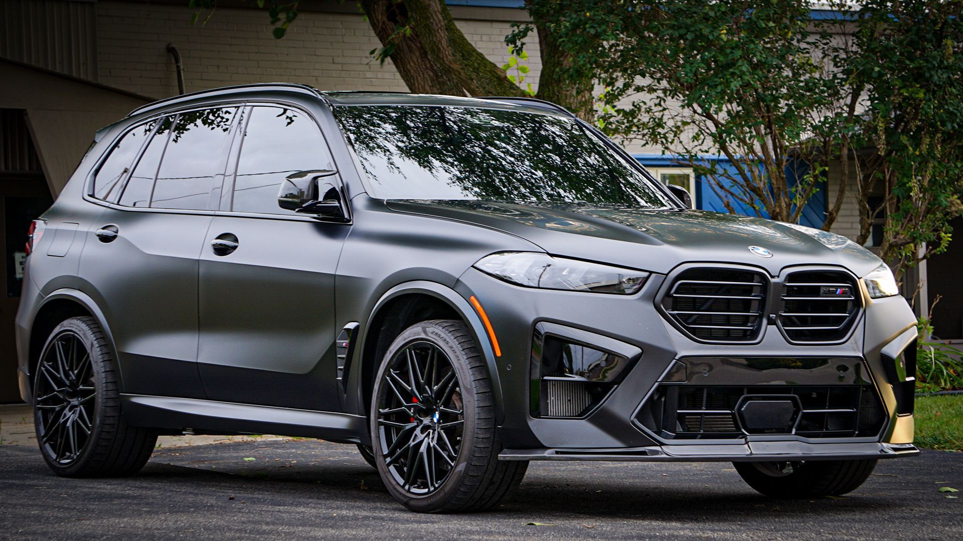 A black bmw x5 is parked in front of a building.