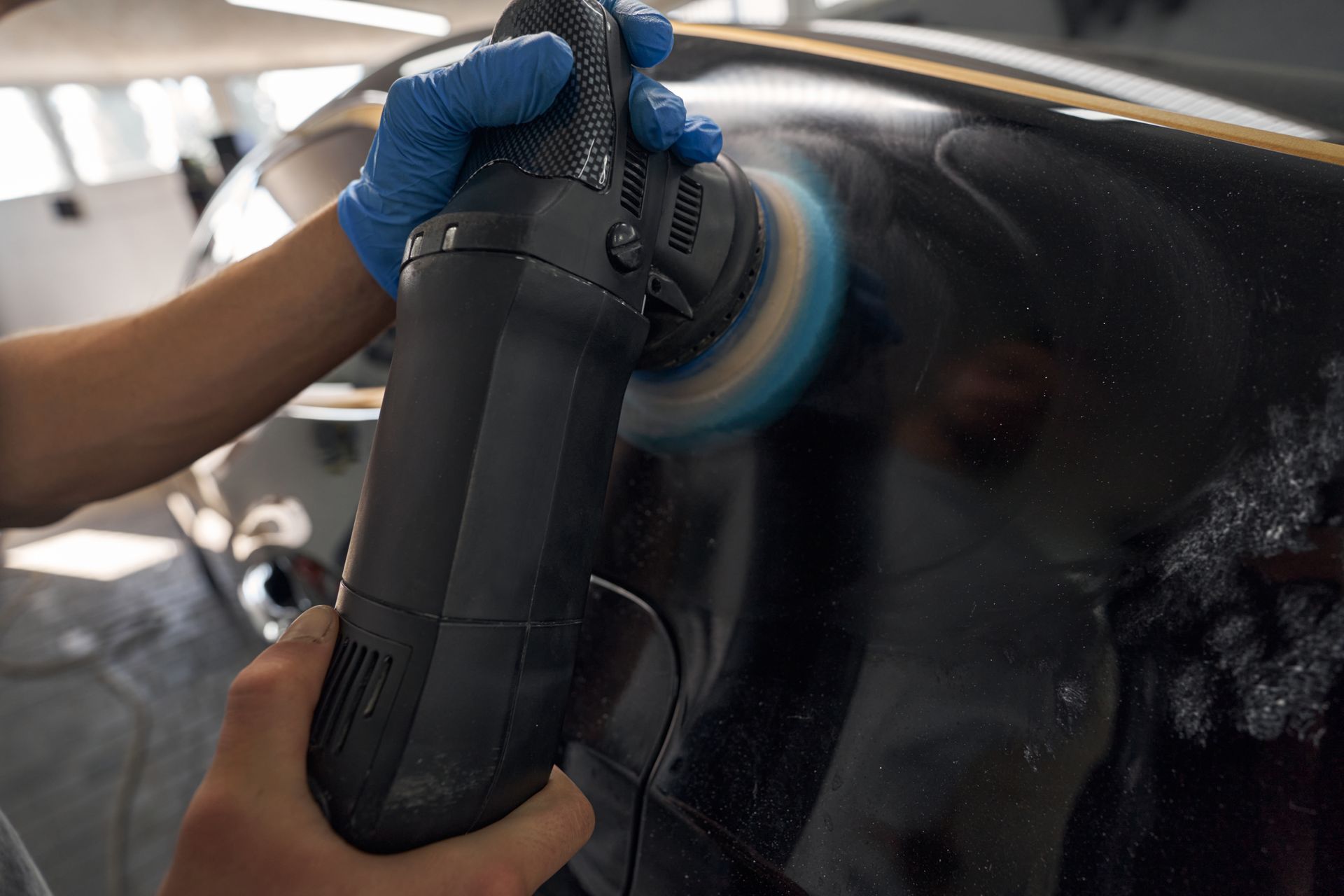 A person is polishing a car windshield with a machine.