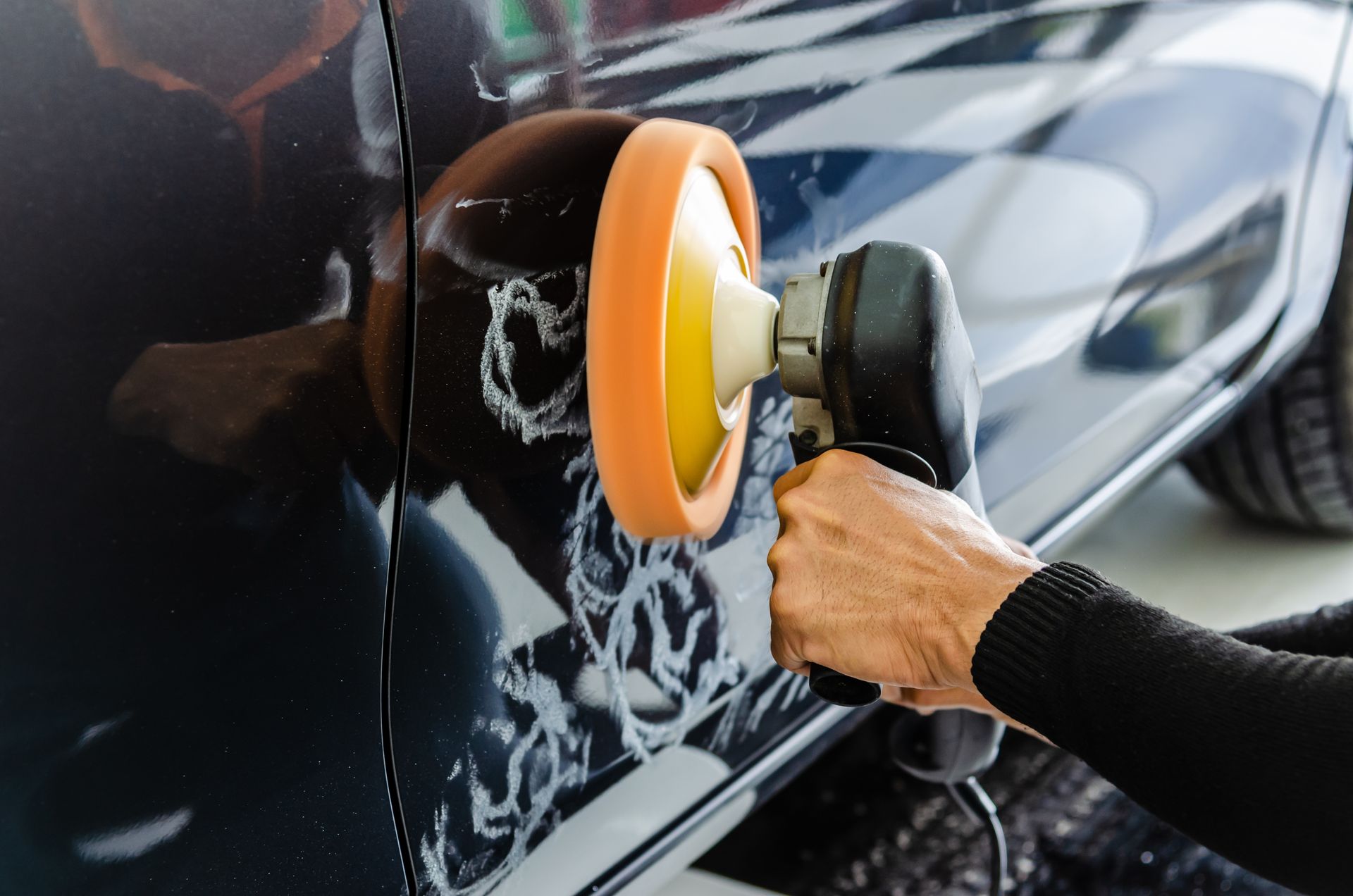 A person is polishing a car with a polisher.