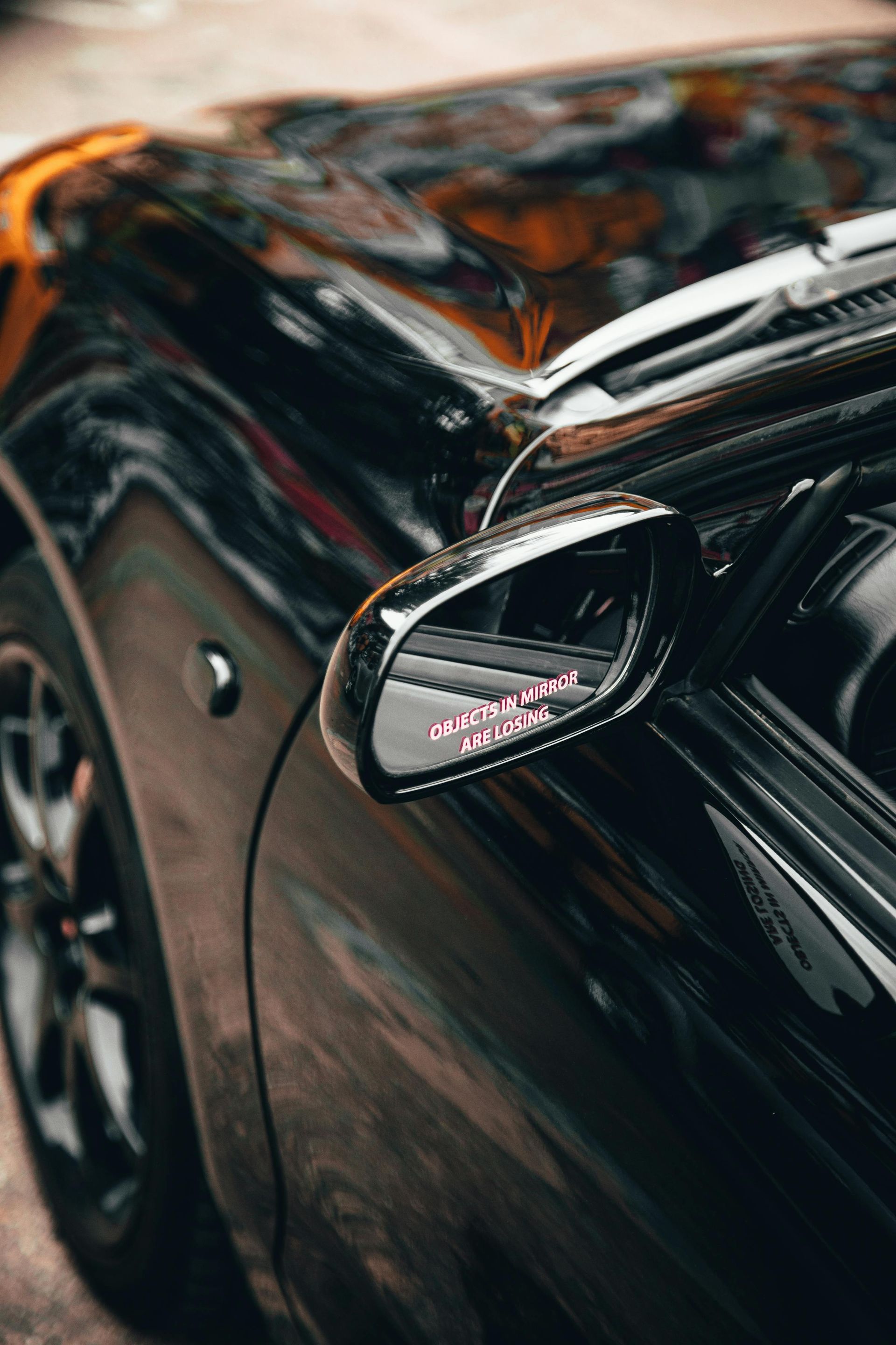 A close up of a side view mirror on a black car.