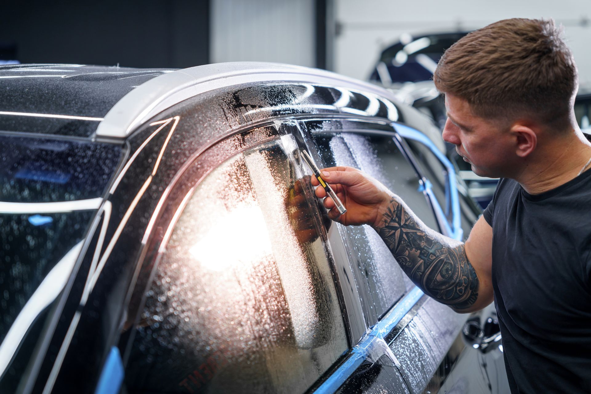 A man is applying tinted glass to a car window.