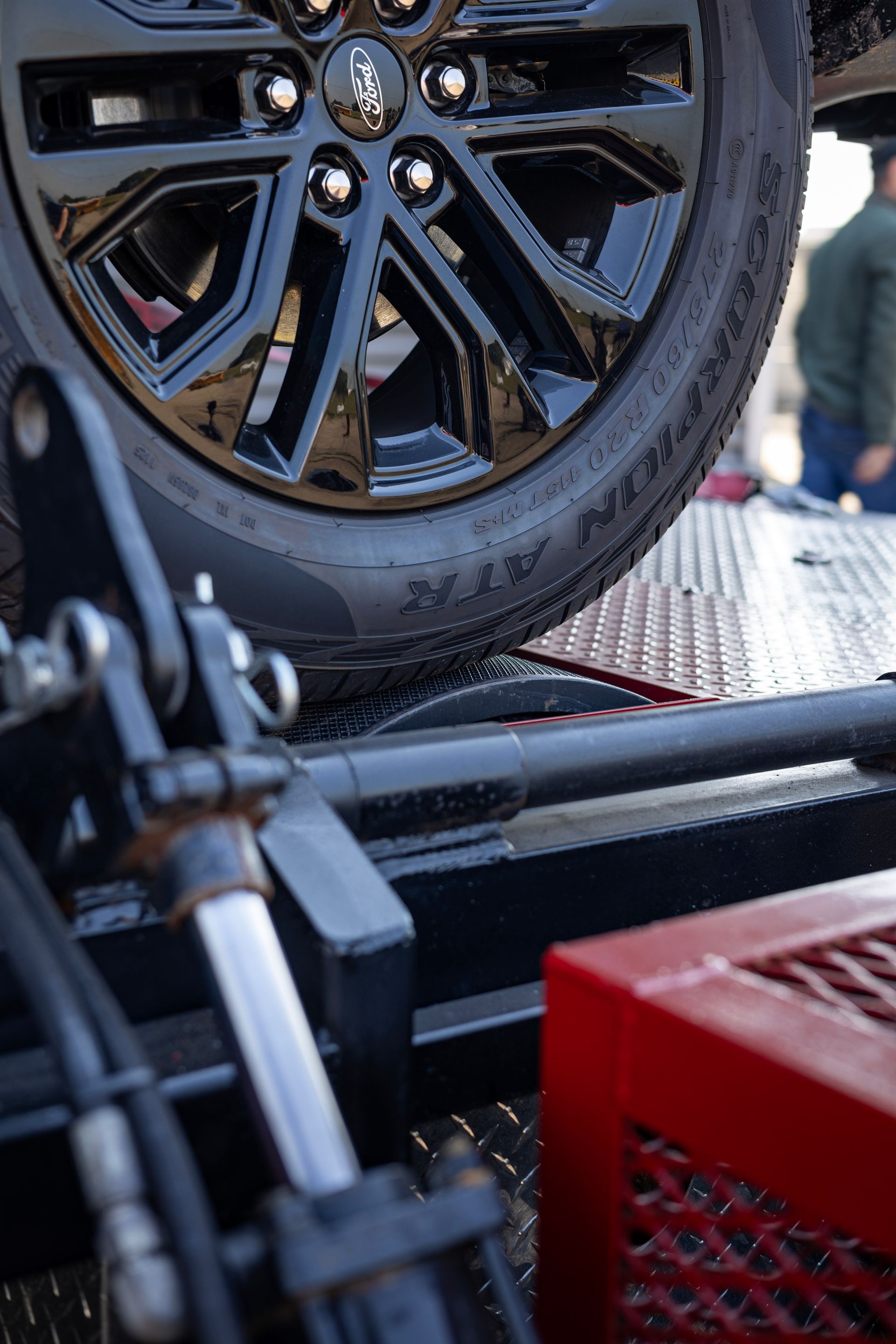 Black vehicle wheel on a tow truck bed; black and red equipment visible.
