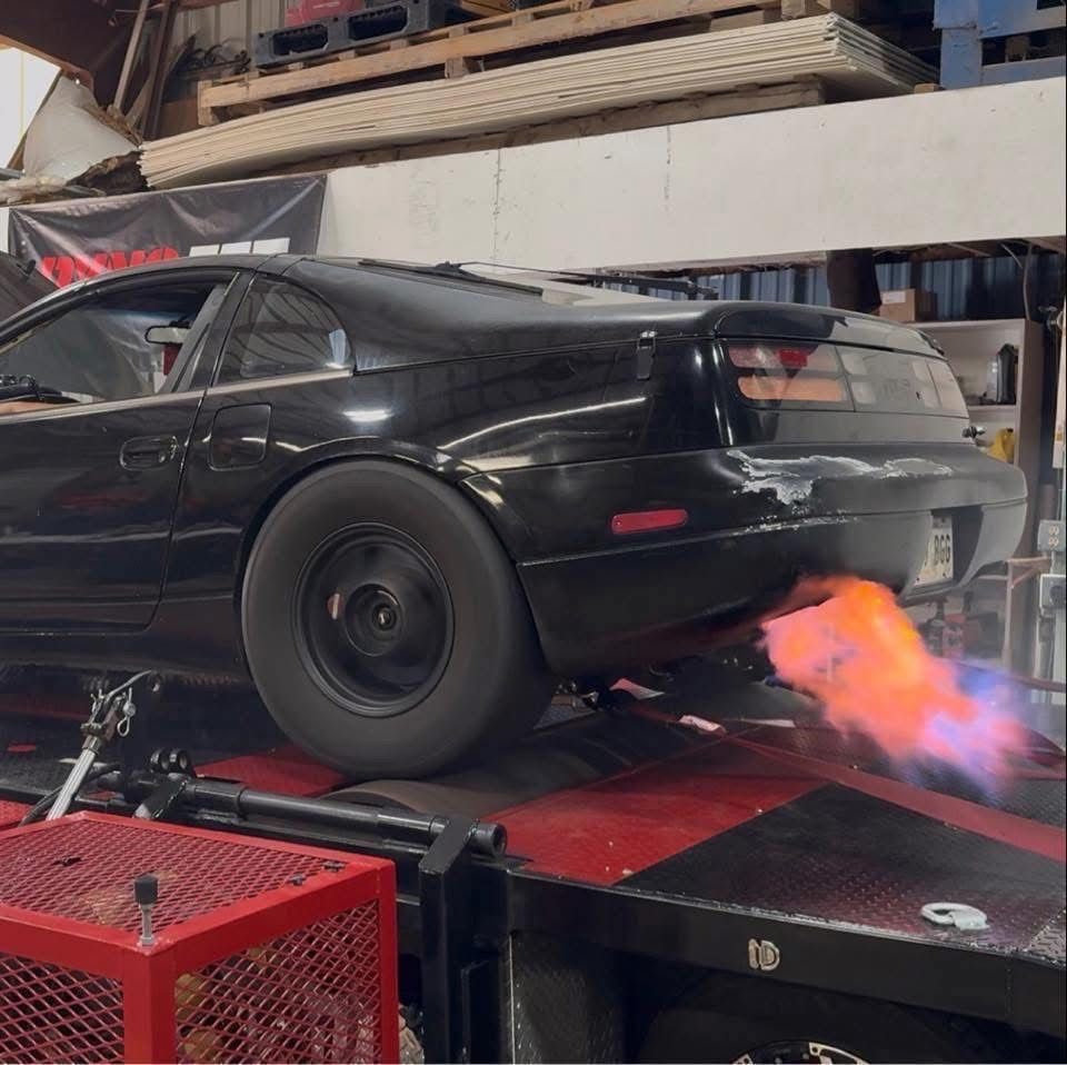 Black sports car on a dynamometer, flames shooting from the exhaust.