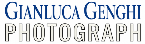 Logo del fotografo Gianluca Genghi, con il simbolo dell'otturatore della macchina fotografica nei colori blu e arancione.