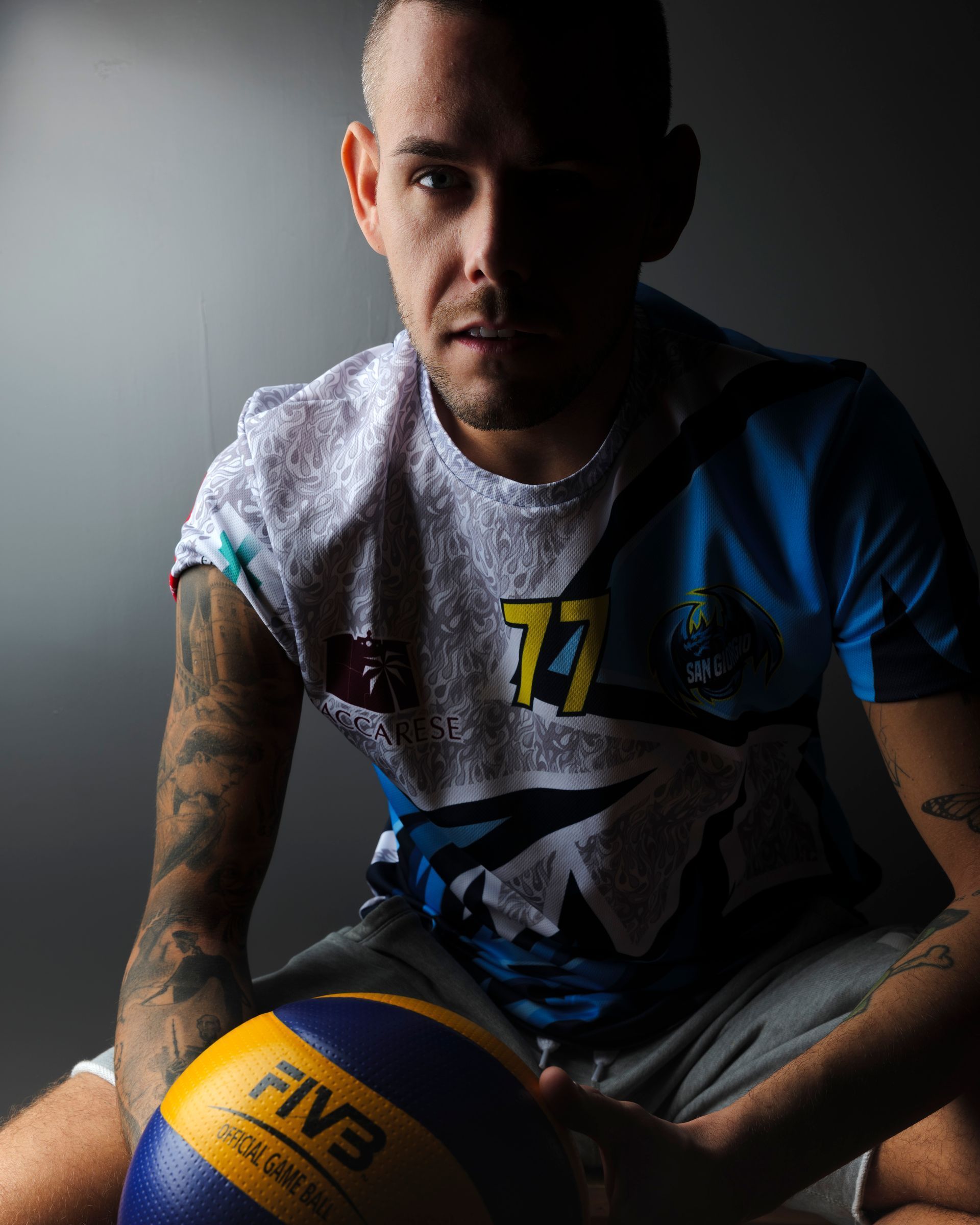 Uomo con tatuaggi, che tiene in mano un pallone da pallavolo e indossa una maglia con il numero 77.