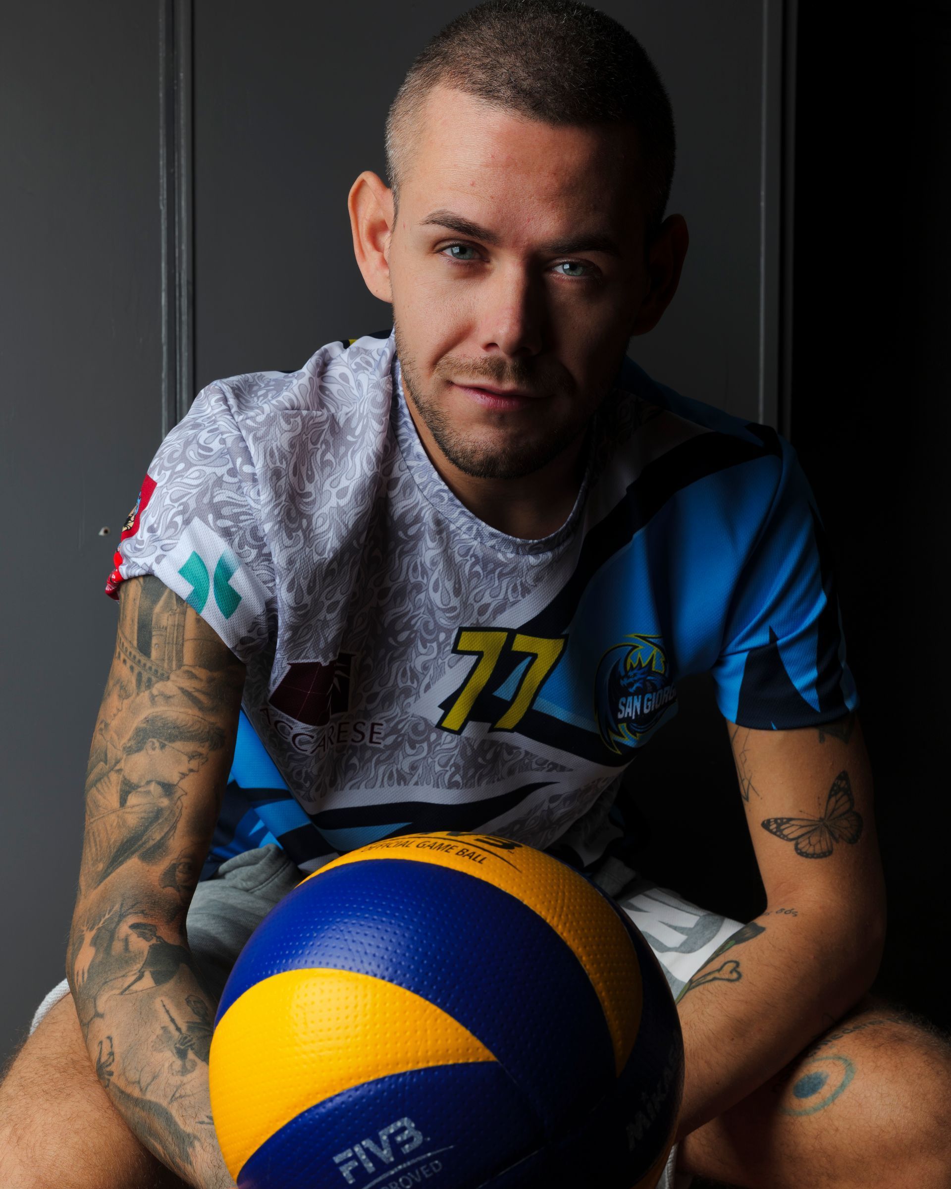 Uomo con tatuaggi, che tiene in mano un pallone da pallavolo e indossa una maglia con il numero 77.