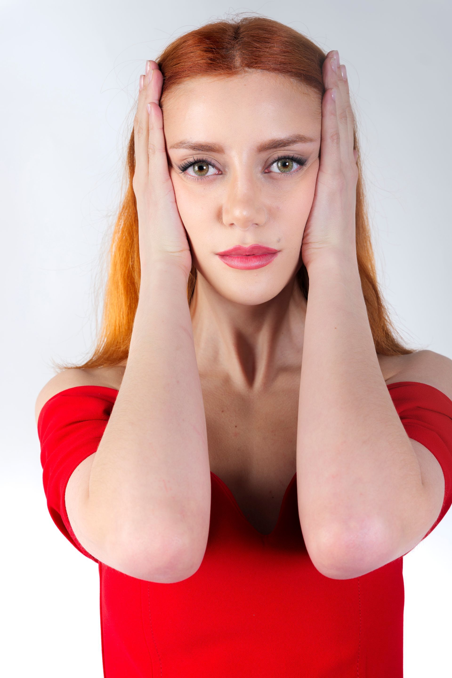 Donna con i capelli rossi e la maglietta che si copre le orecchie con le mani.