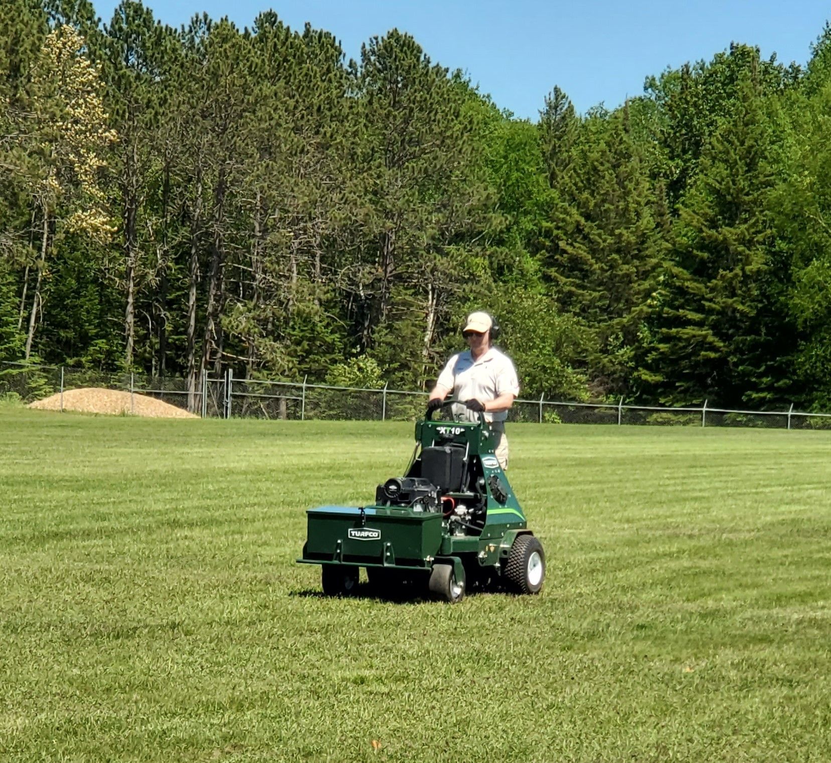 A man is standing in a field with a rake.