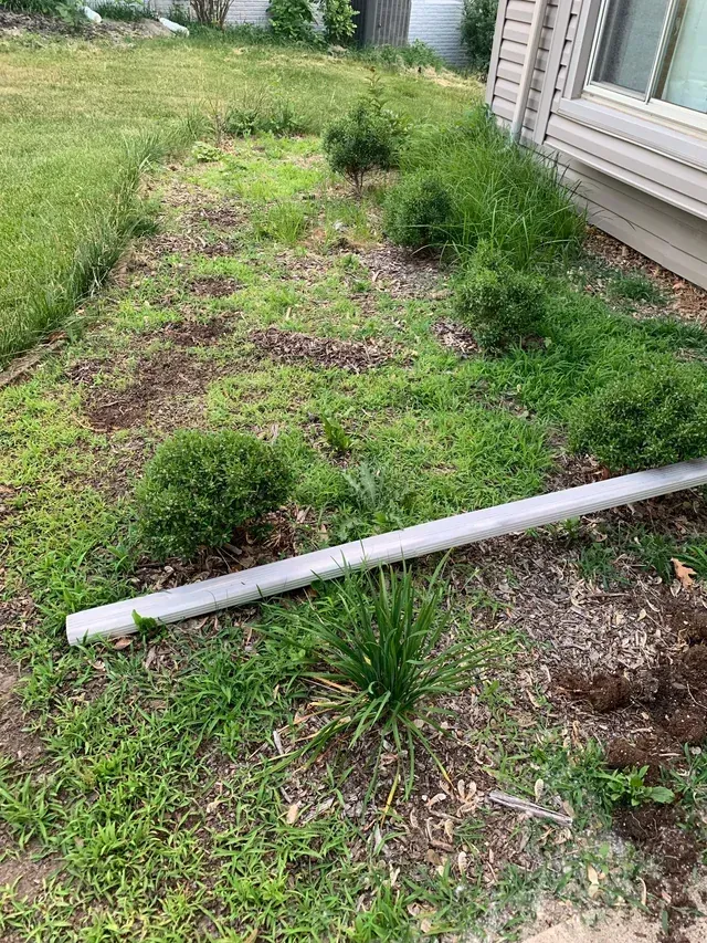 A lawn with a pipe in the middle of it and a house in the background.