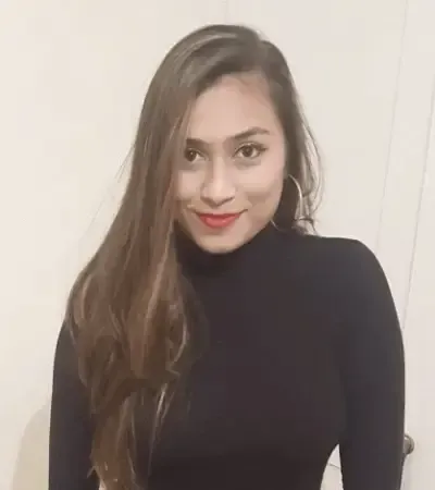 Woman with long brown hair, wearing a black turtleneck, smiling, indoors.