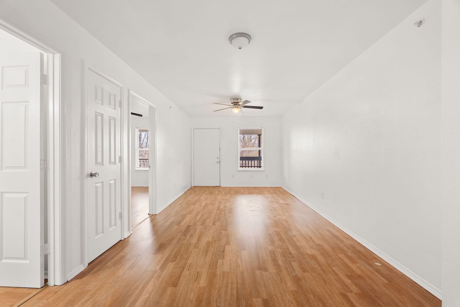 An empty living room with hardwood floors and white walls
