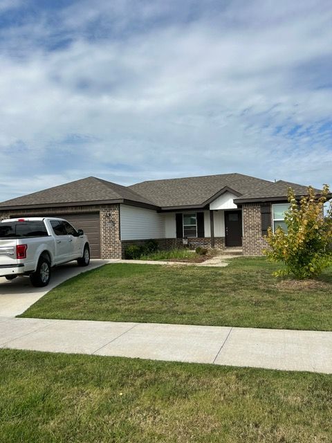 A one-story brick and siding house with a white truck parked in the driveway.
