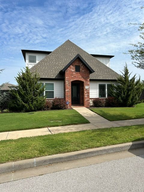 House with white siding, brick entryway, and green lawn.
