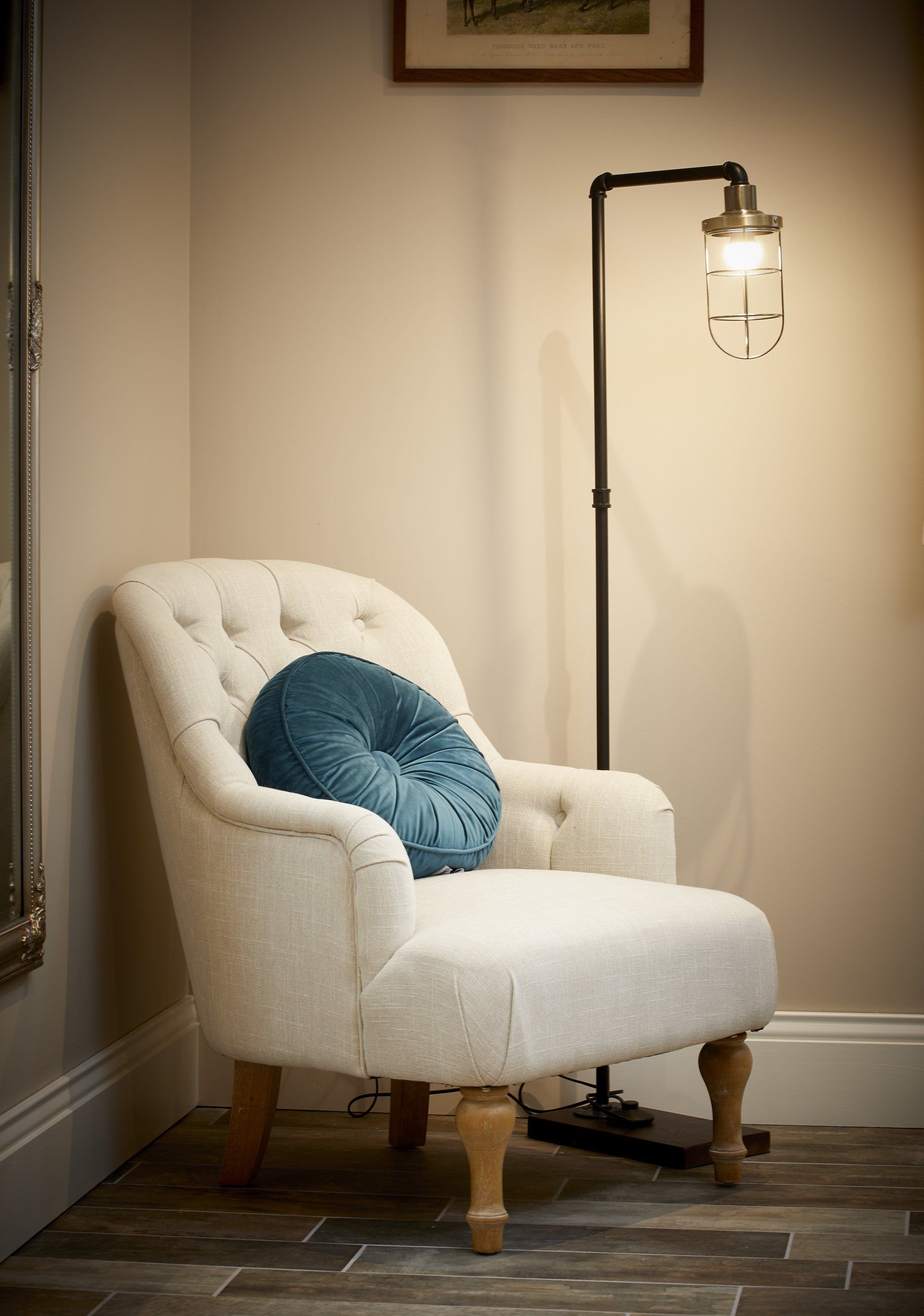 A white chair with a blue pillow on it is sitting next to a lamp.