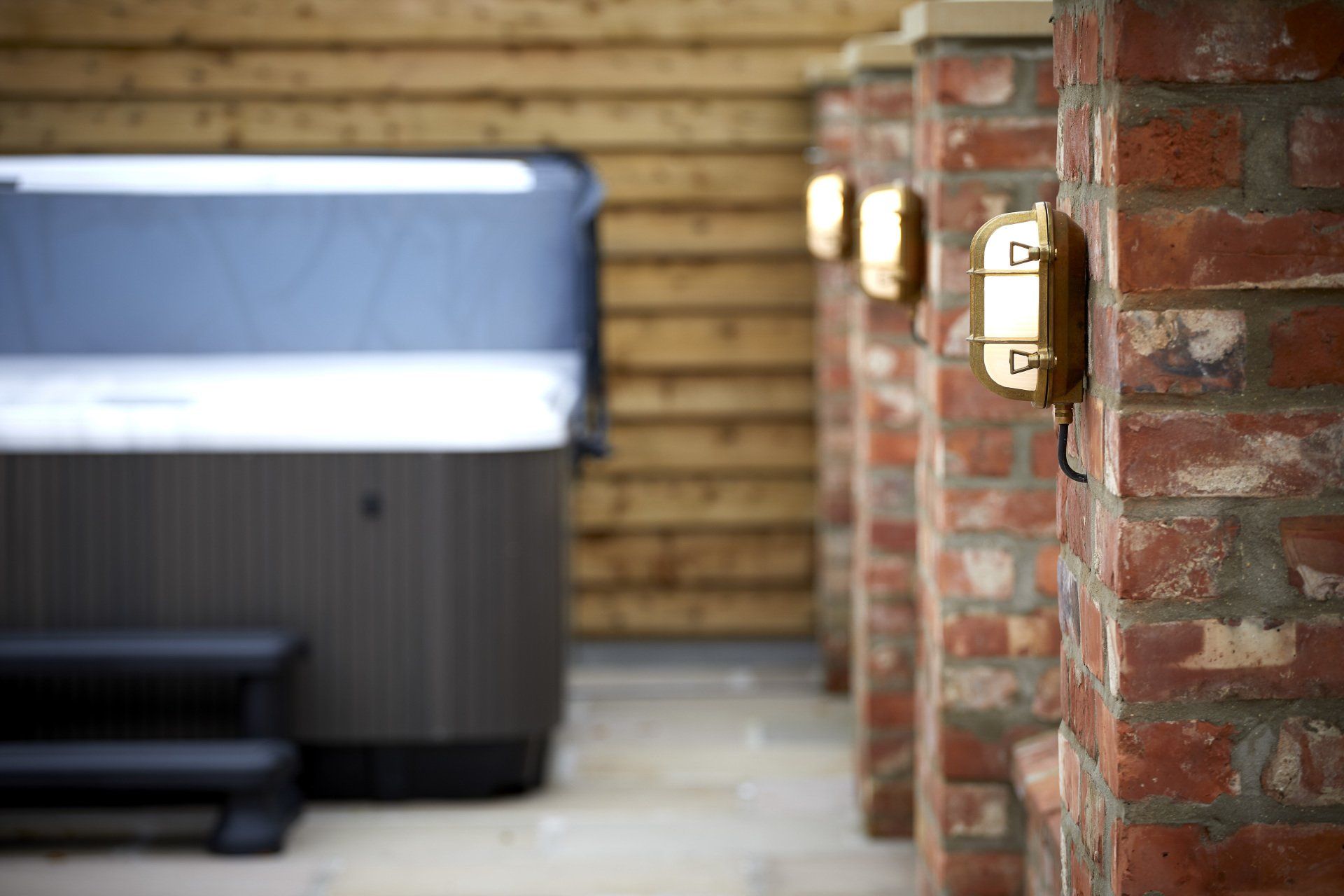 A hot tub is sitting next to a brick wall.
